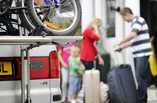 Family with suitcases and a car with bicycles