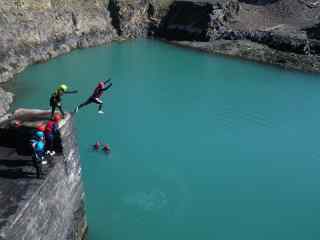 People jumping into water from a cliff